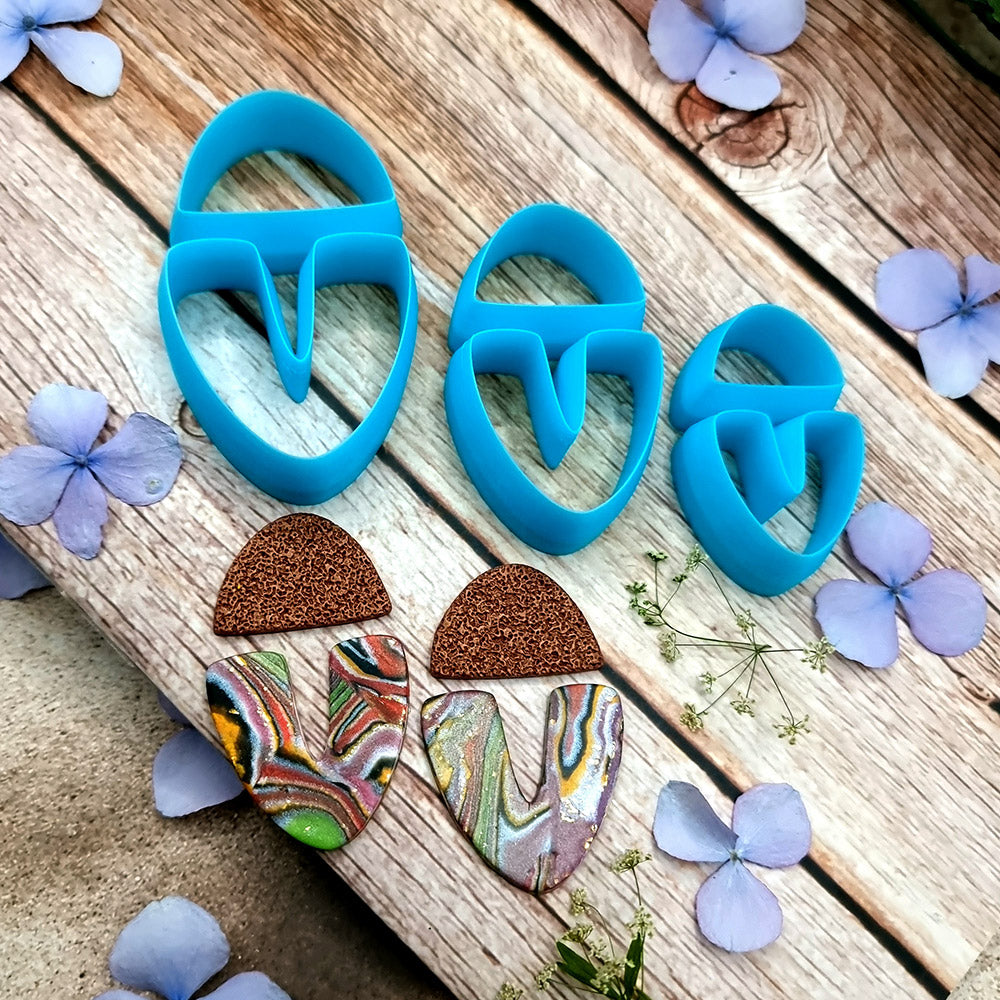 Blue PLA U-shape polymer clay cutters in three sizes cutting a dome cap and U piece, with leopard, plaid and marbled clay pieces by SweetyBijou